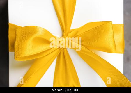 Yellow bow on a gift made of fabric on a white background. Close-up Stock Photo