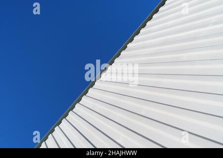 Geometry of a white corrugated metal building against a blue sky. Abstract shapes Stock Photo