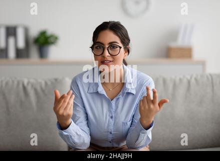 Cheerful young middle eastern female psychologist talking to camera and gesturing during therapy session at clinic Stock Photo