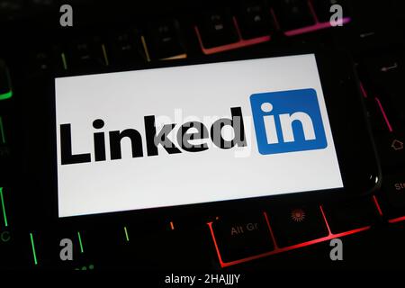 Viersen, Germany - December 9. 2021: Cloesup of mobile phone screen with logo lettering of social network linkedin on computer keyboard Stock Photo