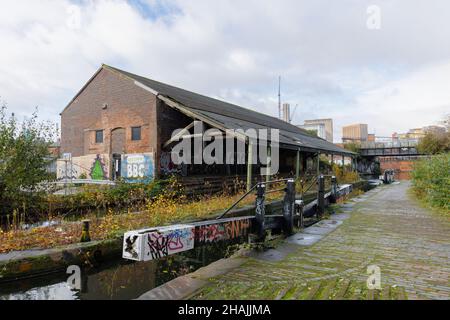 Birmingham West Midlands, UK, December 1st 2021: An abandoned warehouse stands by disused lock gates on the Grand Union Canal near Digbeth Junction. Stock Photo