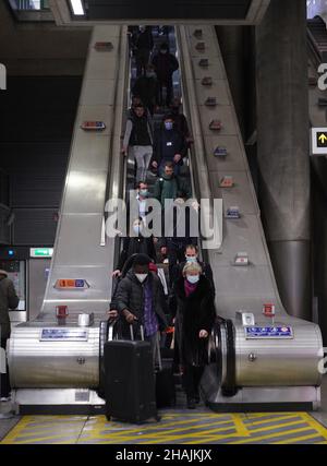 Commuters on an escalator at Canary Wharf Underground station at 16:51 in the evening rush hour, where new restrictions have come into force to slow the spread of the Omicron variant of coronavirus. Picture date: Monday December 13, 2021. Stock Photo