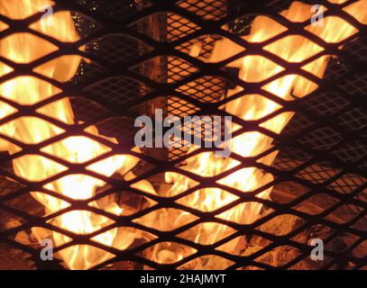 Close up of flames in fire pit with black grate Stock Photo