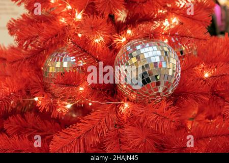 Christmas disco balls on a red Christmas tree. Stock Photo