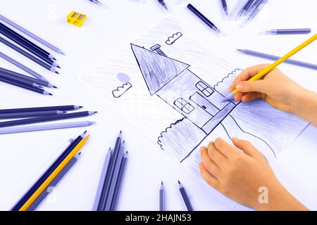 Child girl draws house on a white sheet. Color of 2022 year Stock Photo