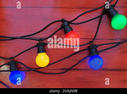 Christmas garland with multi-colored light bulbs on a brown background. Stock Photo