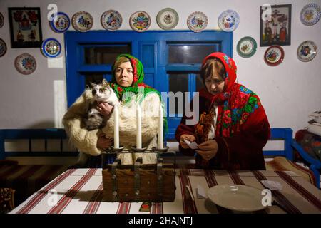 Non Exclusive: UZHHOROD, UKRAINE - DECEMBER 10, 2021 - Two women in a traditional Ukrainian costume sit at the table during the Andriivski Vechornytsi Stock Photo