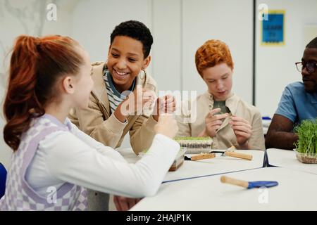 Diverse group of children experimenting in biology class, focus on smiling African-American girl Stock Photo