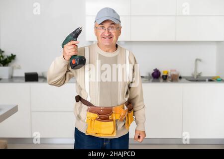 Mature Male Serviceman Repairing With Toolbox In Kitchen Stock Photo
