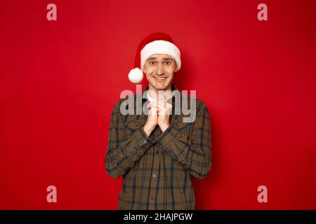 man in casual clothes Santa hat made wish waiting for magic miracles highlighted in red background Stock Photo