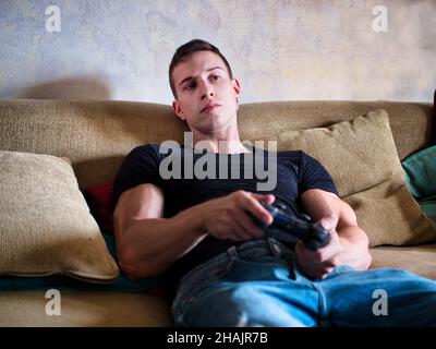 Attractive guy playing videogames with joystick in hand Stock Photo