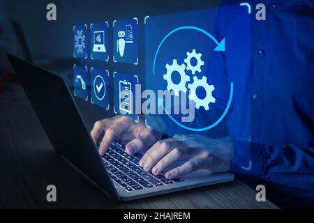 Robotic Process Automation (RPA) technology to automate business tasks with AI. Concept with expert setting up automated software on laptop computer. Stock Photo