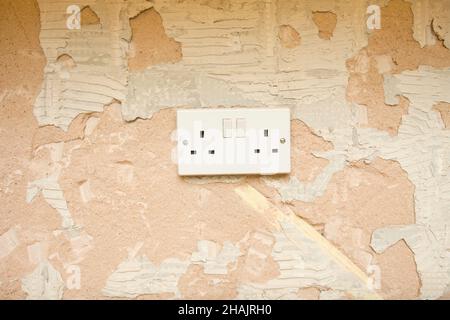 Double plug socket on old plastered wall. uk Stock Photo