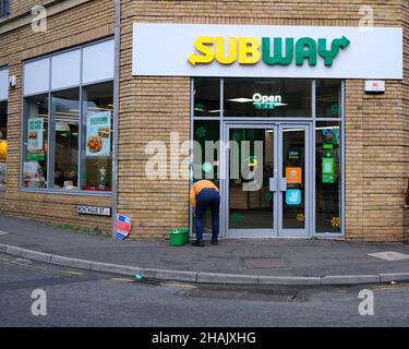 December 2021 - Man cleaning the windows of a Subway take away sandwich shop in Bristol, England, UK., Stock Photo