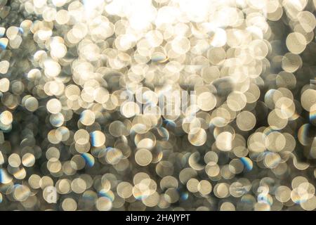 Lights bokeh on black background. Christmas festive decoration. Abstract pattern, silver white glitter, sparkling blur backdrop. Stock Photo