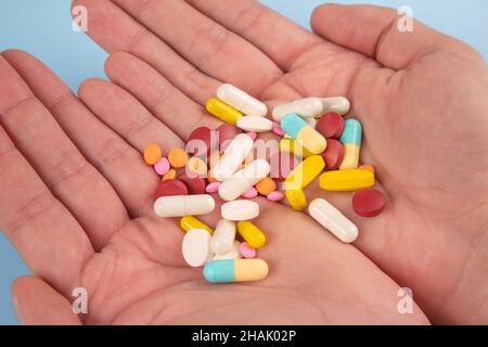 Man holding assorted multicolored medicine pills, capsules and tablets in his hands. A handful of pills. Immune system vitamins and supplemets Stock Photo