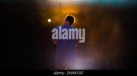 View from the back of a man playing the violin on stage Stock Photo