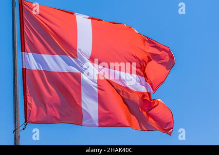 Danish national flag waving on blue sky background. Kingdom of Denmark, DK