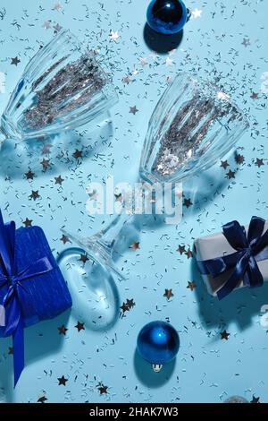Champagne glasses with confetti and gifts on blue background Stock Photo