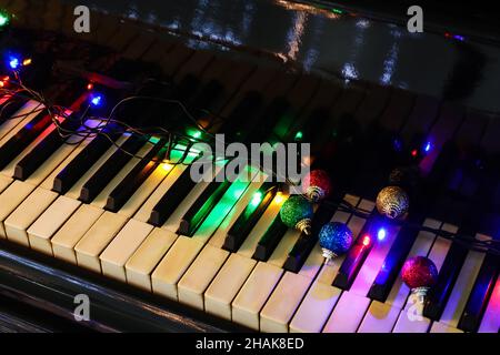 Christmas balls with glowing lights on piano keys Stock Photo