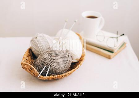 Natural wool in balls of various pastel colors in a wicker basket. Knitting threads close-up on a light background. Stock Photo