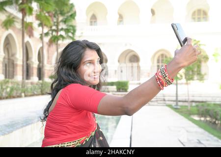 Asian Indian ethnic woman using smartphone to take self portrait or video chat. Stock Photo