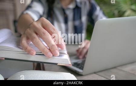 Woman's hand turning pages of a book, close up. Home setting. Stock Photo