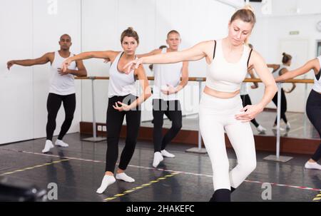 Concentrated women and men rehearsing ballet dance in studio. Stock Photo