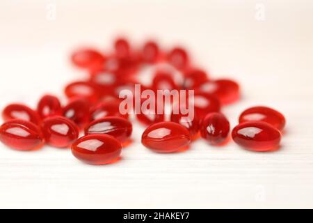 Krill oil red gelatin capsules on a white wooden background .omega fatty acids