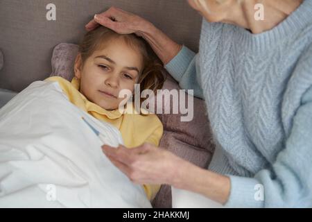 Sad little kid feeling sick and staying in bed Stock Photo