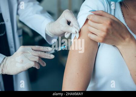 Close up portrait of a doctor's hands making a vaccination in the shoulder of patient's arm. Flu vaccination. Coronavirus. Covid-19 vaccine. Stock Photo