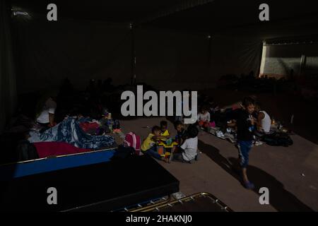 Mexico City, Mexico. 13th Dec, 2021. children play inside a large tent as darkness sets in for the night in the makeshift shelter. Around 500 people arrived in Mexico City as part of a caravan of migrants formed of many Central American countries. They planned to rest for four days in the Casa de Peregrina, PilgrimÕs House, before making their way to the border with the United States of America to seek asylum. Credit: Lexie Harrison-Cripps/Alamy Live News Stock Photo