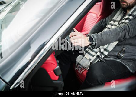 New Premium Car Buyer Inside the Vehicle. Dealership Showroom Display. Men Fitting Himself. Automotive Theme. Stock Photo