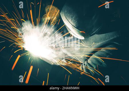Professional Welder is Welding Two Metal Parts Together. Sparks Flying All Around. Metal Industry Theme. Stock Photo