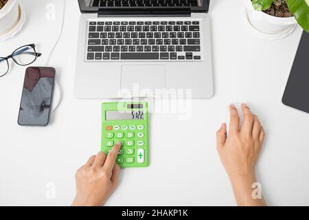Accountant working and analyzing financial calculating with calculator and laptop computer income-expenditure at office desktop, Business financial an Stock Photo