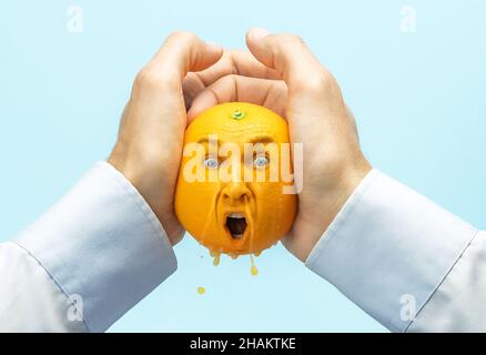 The employer squeezes all the strength or juice out of the employee. Coming up with ideas, squeezing creativity out of yourself. Hands pour out juice from an orange, an orange with a face. Stock Photo