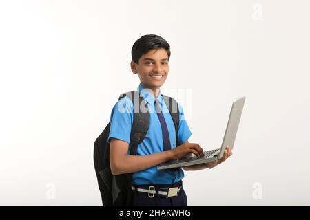 Indian school boy in uniform and using laptop on white background. Stock Photo