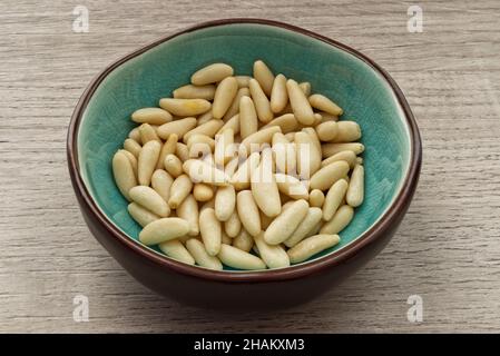 Pine nuts in a bowl isolated on wooden background Stock Photo