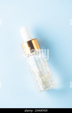 bottle of 24k gold serum on a blue background. The concept of skin care at home Stock Photo