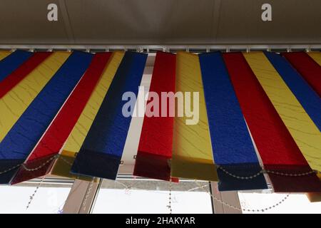 Hanging fabric blinds in three colors on a white window background Stock Photo