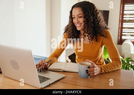 African American female business woman smiling working from home typing on laptop  Stock Photo