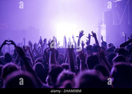 Crowd of people celebrating the New Year's Eve at a party. Stage lights in the background Stock Photo