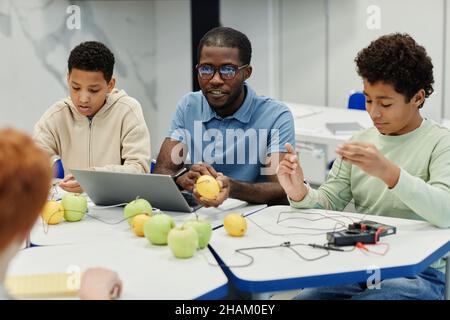 Portrait of male African-American teacher working on science experiments with diverse group of children Stock Photo