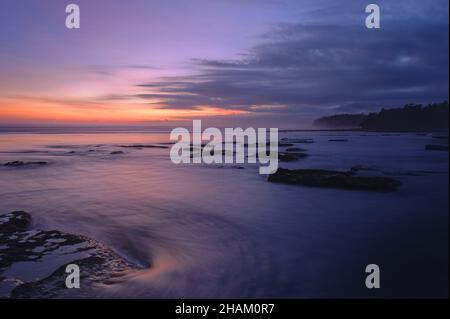 After sunset the last ray of light on this beach gave me this beautiful purple sky with a very nice yellow color reflection on the water Stock Photo