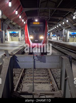 Zurich, Switzerland - November 30, 2021: Train arriving at night to the railway station in Zurich Stock Photo