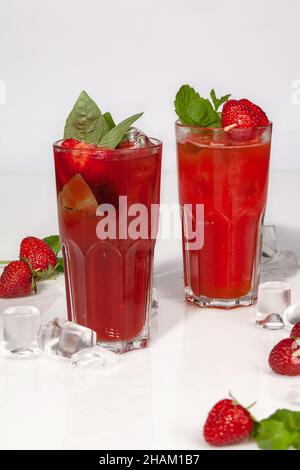 Two glasses of iced strawberry drinks with basil and mint Stock Photo