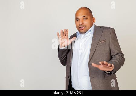 Portrait of shocked young African American businessman guy, scared and frightened by fear expression, stopped hand gesture, shouting in shock. Panic Stock Photo