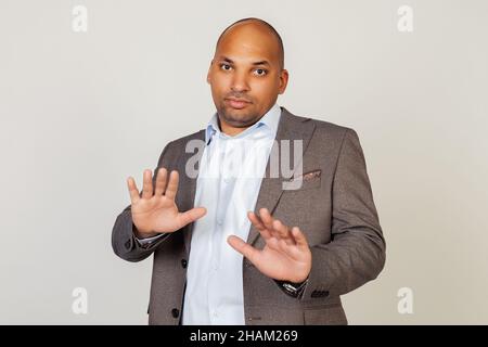Portrait of shocked young African American businessman guy, scared and frightened by fear expression, stopped hand gesture, shouting in shock. Panic Stock Photo