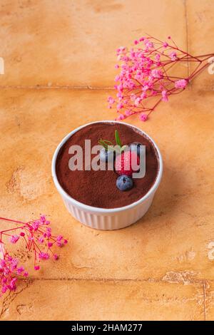 dessert tiramisu with berries on brown background with pink flowers Stock Photo