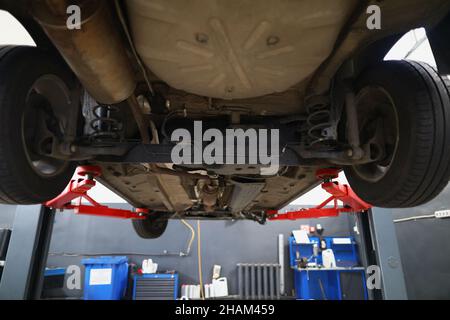 Car lifted in maintenance service to check condition, undercarriage of automobile Stock Photo